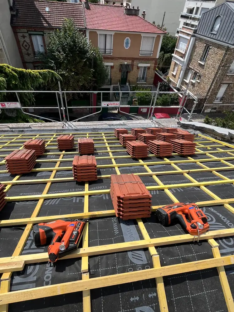 Chantier en cours : écran de sous-toiture et liteaux posés, tuiles prêtes
